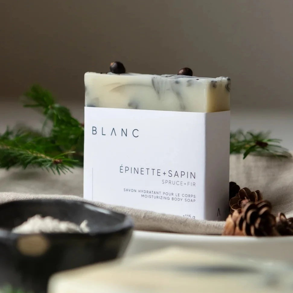 BLANC SAVONNERIE Barre hydratante et nourrissante Ce classique hivernal transporte au cœur la forêt boréale avec son franc mélange d'huiles essentielles d'épinette noire et de sapin baumier. Formulé avec des huiles et beurres hydratants et nourrissants, ce savon offre une mousse généreuse et lave tout en douceur grâce à l’ajout d’argile blanche. Indiqué pour tous les types de peau. IngrédientsHuiles et beurres saponifiés (olive, coco bio + équitable, tournesol bio du Québec, karité bio + équitable, ricin b