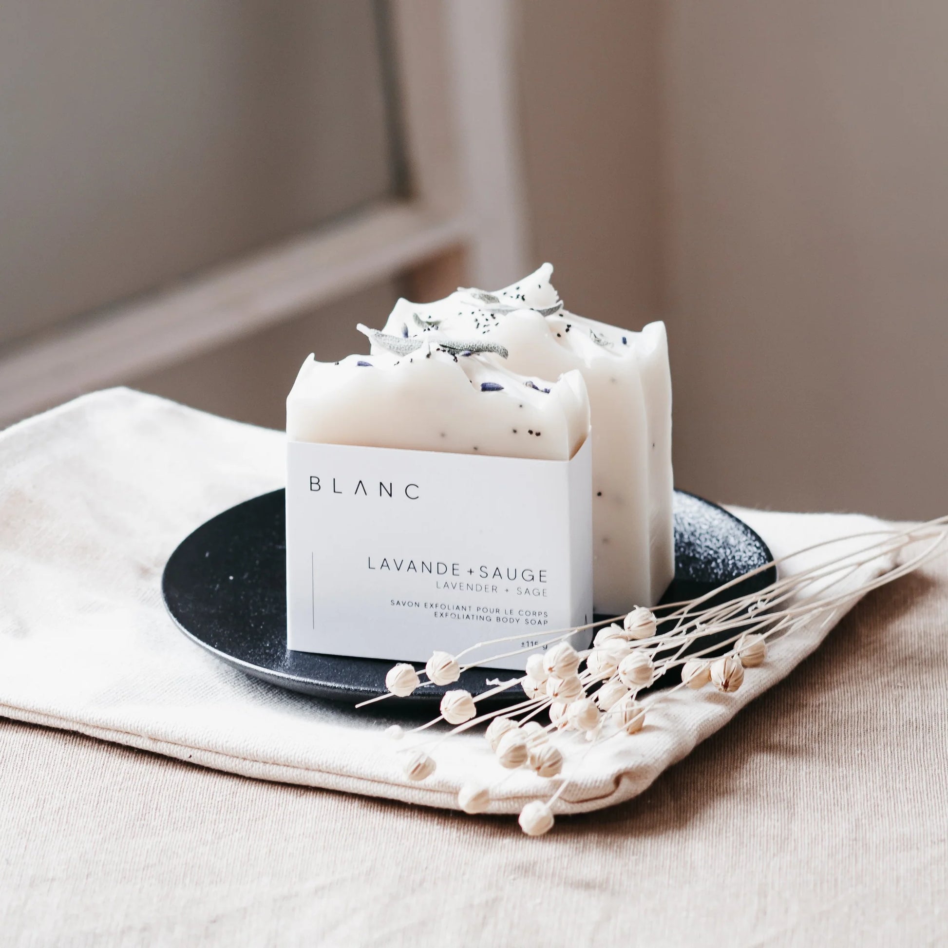 BLANC SAVONNERIE Soin exfoliant et hydratant Le beurre de karité brut contenu dans ce savon contribue à protéger, adoucir et restructurer les peaux abîmées. Combiné aux propriétés apaisantes et relaxantes des huiles essentielles de lavande et de sauge, cette barre constitue un soin détente par excellence. Les graines de pavot procurent une exfoliation légère, tandis que l'ajout d'argile blanche lave tout en douceur. Pour tout type de peau. IngrédientsHuiles et beurres saponifiés (olive, coco bio +équitable,